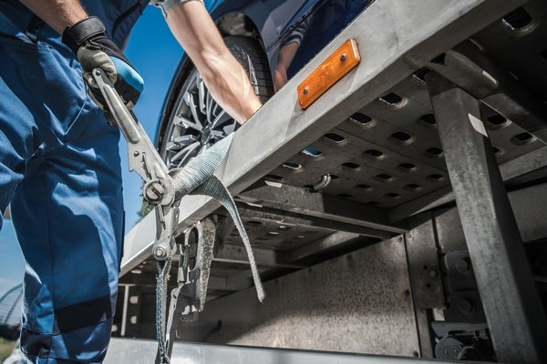 Worker securing car on tow truck